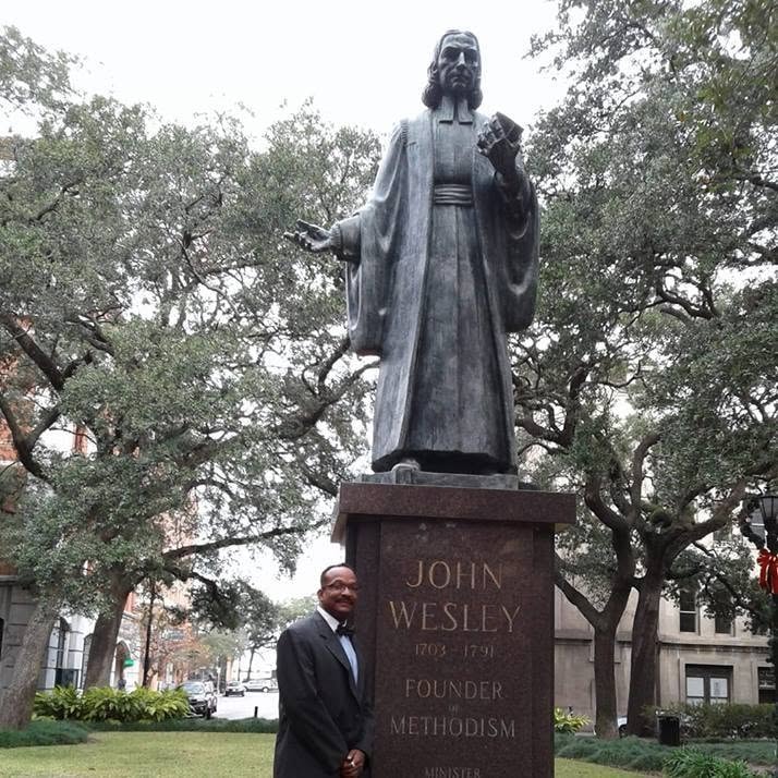 Rev. Ford standing beside the John Wesley statue — Founder of Methodism, 1703–1791